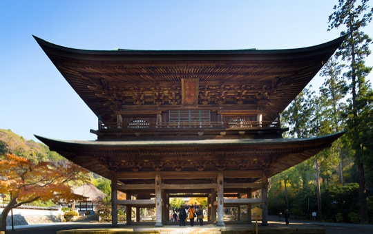 The tall two-storey wooden Sanmon gate among trees at Engaku-ji Zen temple, Kamakura