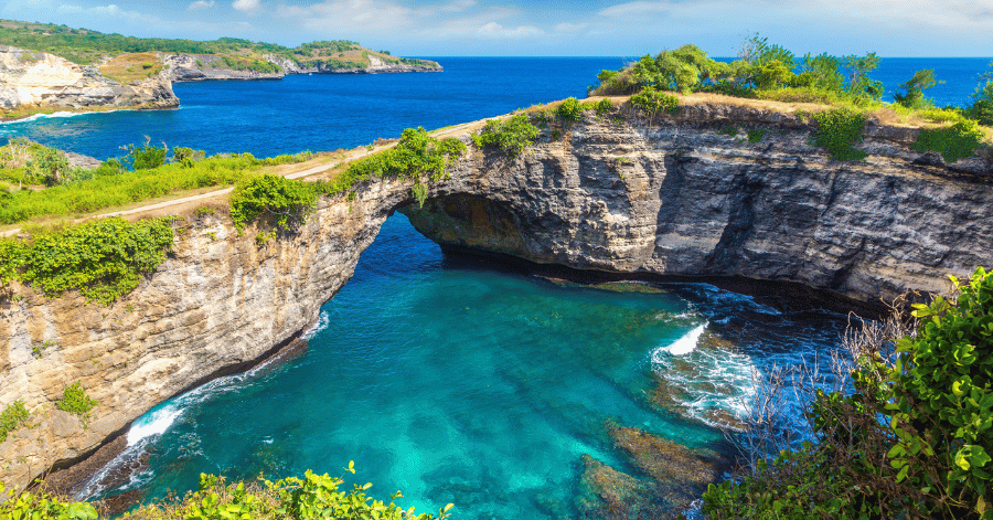 Nusa Penida's cliffs and a natural coastal rock arch above a turquoise cove