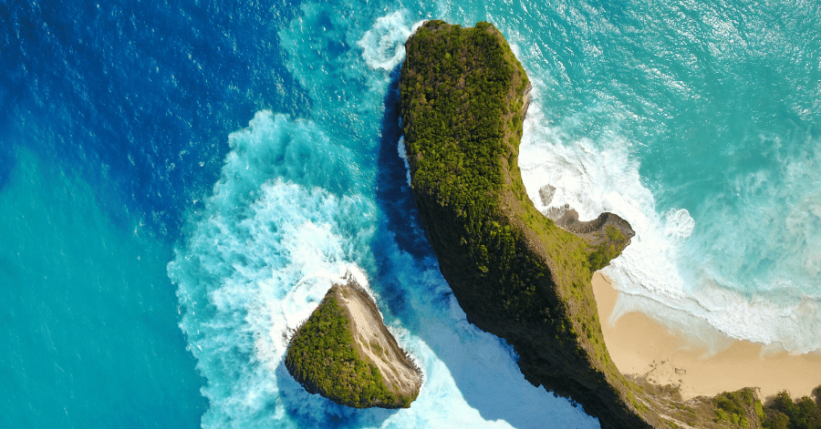 Aerial view of Kelingking Beach's T-Rex-shaped headland and white-sand cove, Nusa Penida