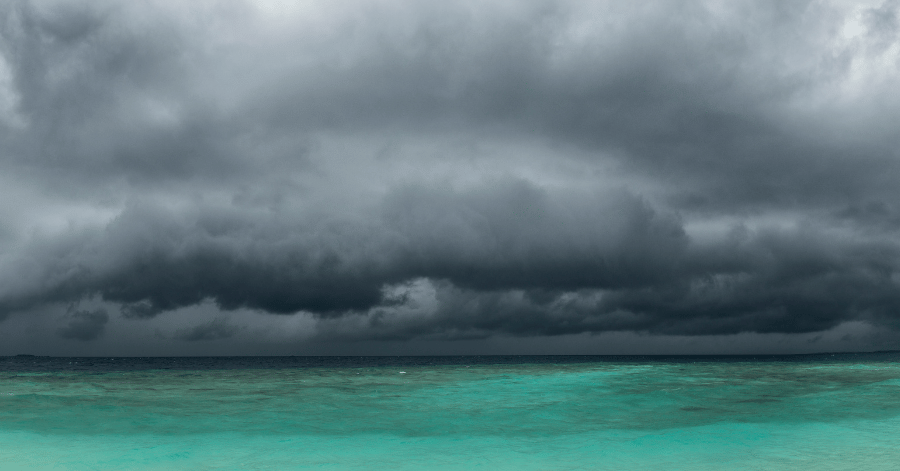 Dark grey monsoon storm clouds building over a calm turquoise Maldives sea
