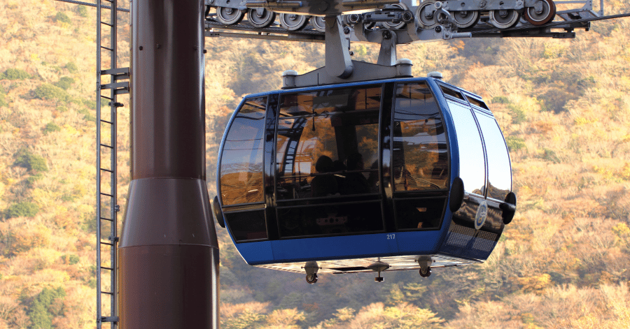 A blue Hakone Ropeway gondola in close-up against autumn foliage