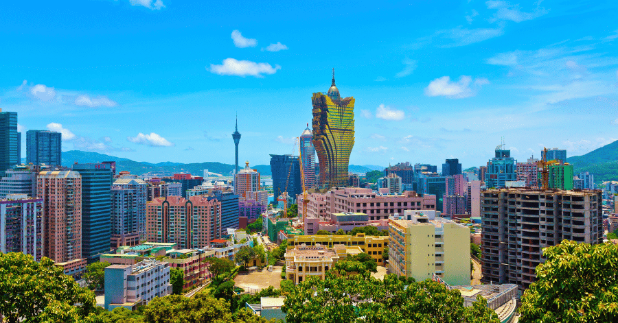 Macau's daytime skyline with the golden Grand Lisboa tower and Macau Tower under a blue sky