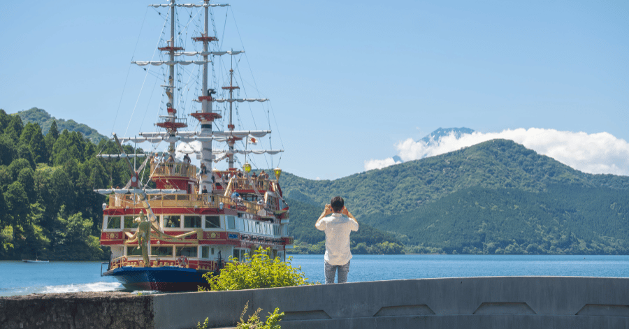 A red and gold pirate-style sightseeing ship on Lake Ashi as a visitor photographs it