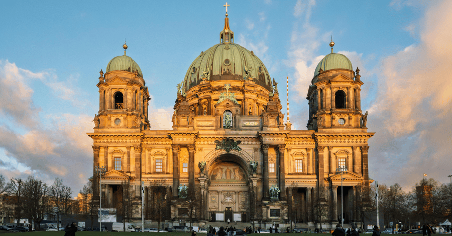 Berlin Cathedral (Berliner Dom) with its green copper domes, lit warm by a low sun against a blue sky