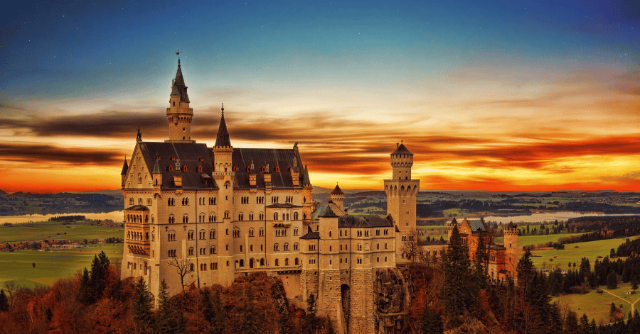 Neuschwanstein Castle on a wooded hill above the Bavarian countryside at sunset