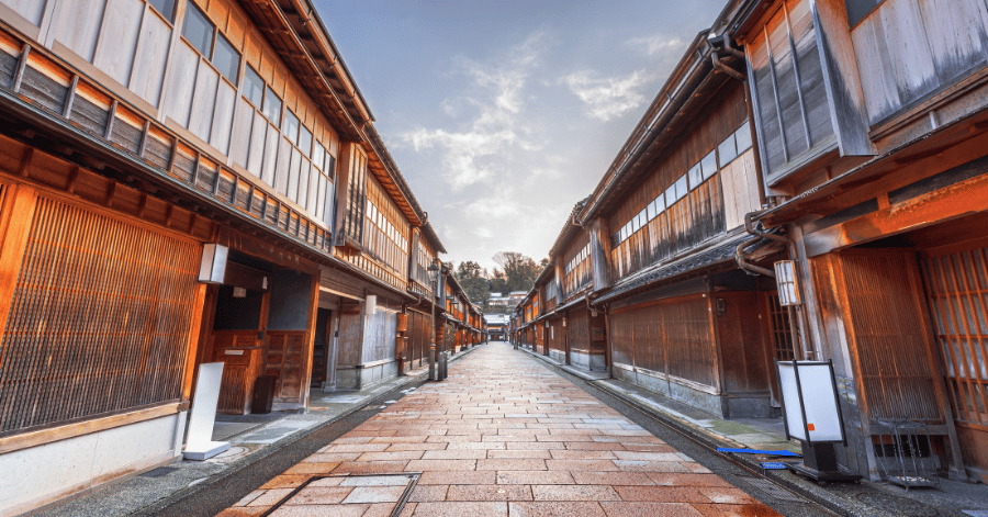 Wide stone-paved street lined with historic wooden teahouses in Kanazawa at dawn