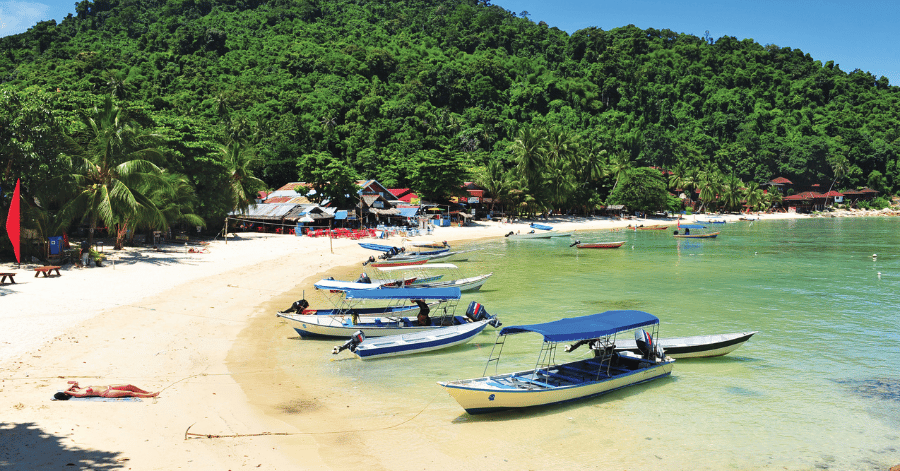 Boats and wooden chalets along a quiet, palm-fringed Perhentian Besar shore