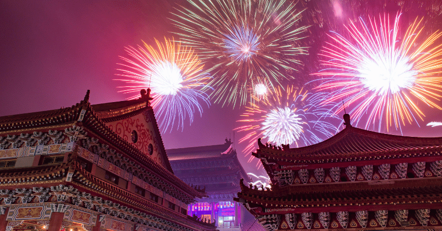 Colourful fireworks bursting over the ornate roofs of a traditional Taiwanese temple at night