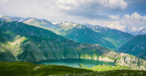 A deep-green mountain lake among lush peaks and snow-capped ridges in Kazakhstan