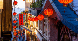 Red lanterns lining the stepped lanes of Jiufen Old Street above the sea at golden hour in Taiwan