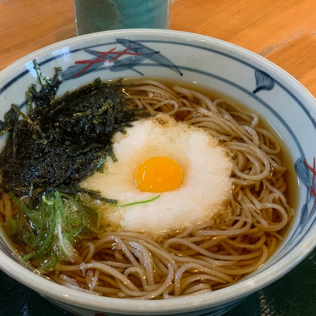 A bowl of buckwheat soba topped with grated yam, an egg yolk and nori