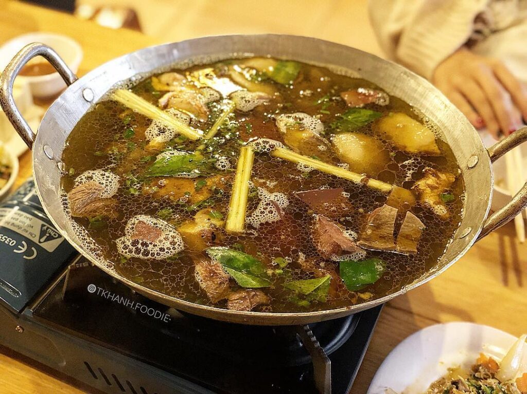 A simmering pot of thang co, the dark H'mong stew of meat, offal and lemongrass, on a tabletop burner