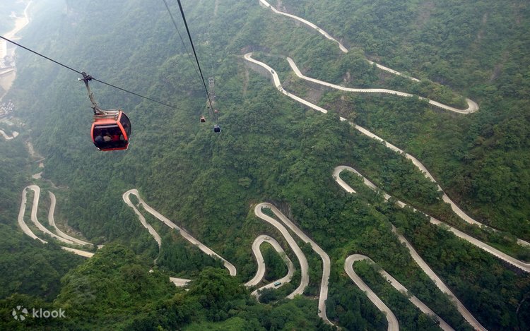 A red cable-car gondola above the hairpin turns of Tongtian Avenue on Tianmen Mountain