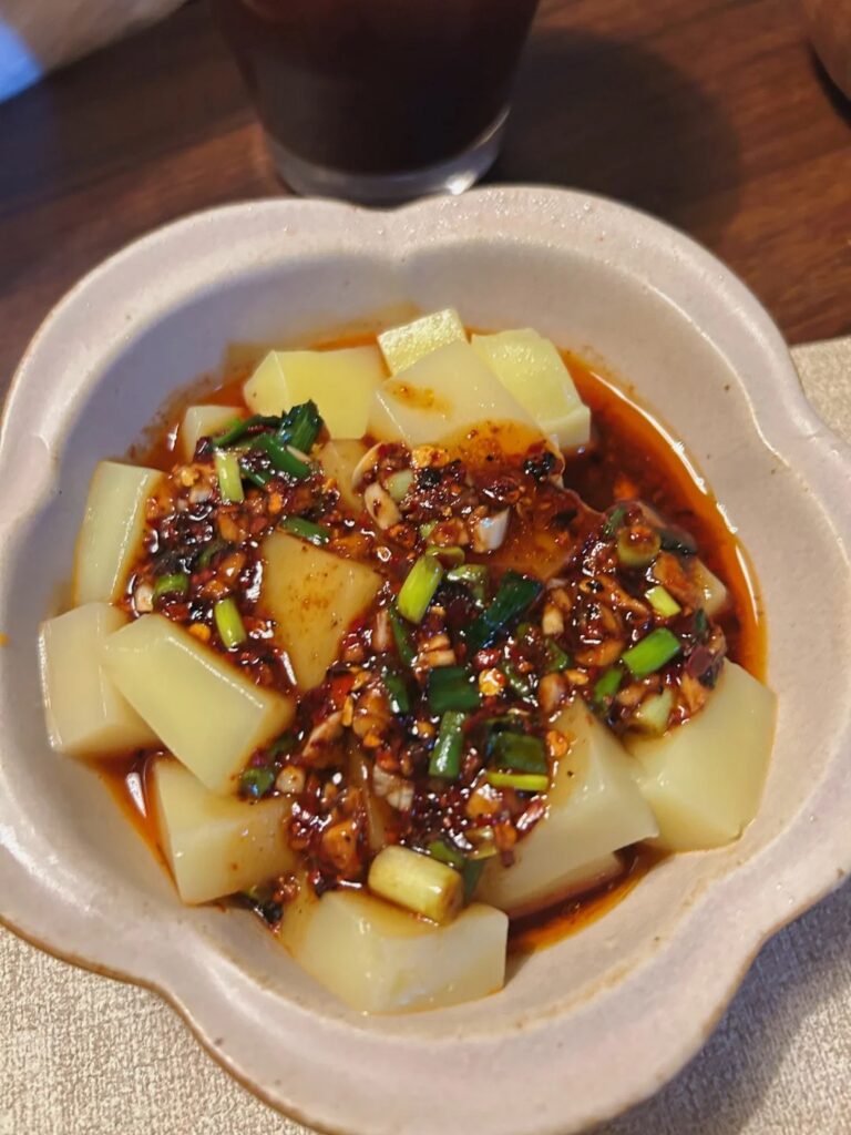 A bowl of soft rice-tofu cubes dressed in chilli oil, garlic and spring onion