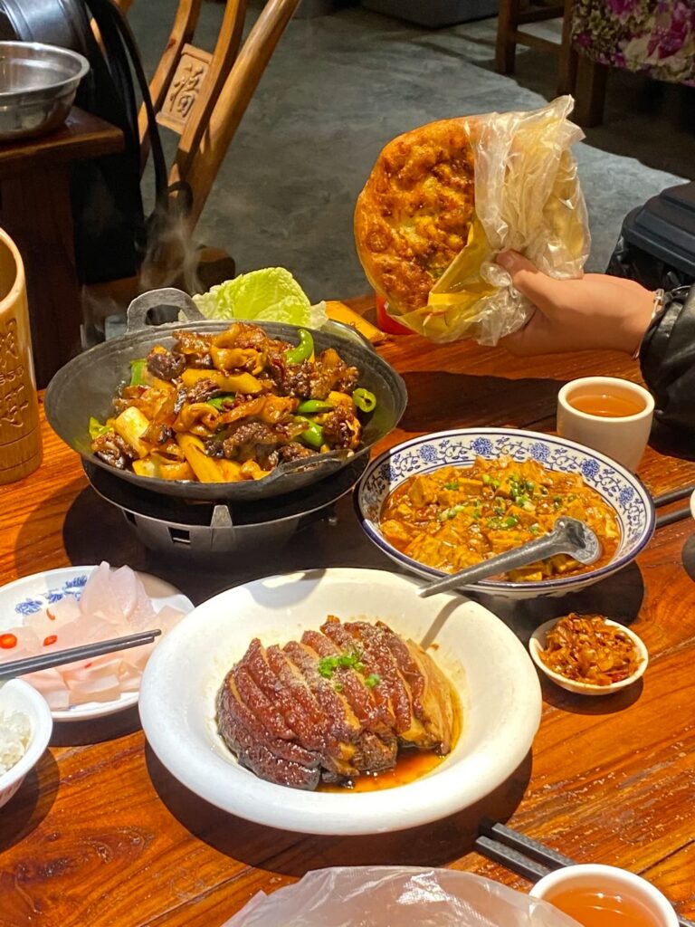 A sizzling Tujia sanxiaguo dry pot of cured meat and chillies with side dishes