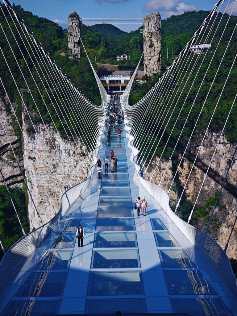 Visitors crossing the glass-floored Zhangjiajie Grand Canyon bridge high above a gorge
