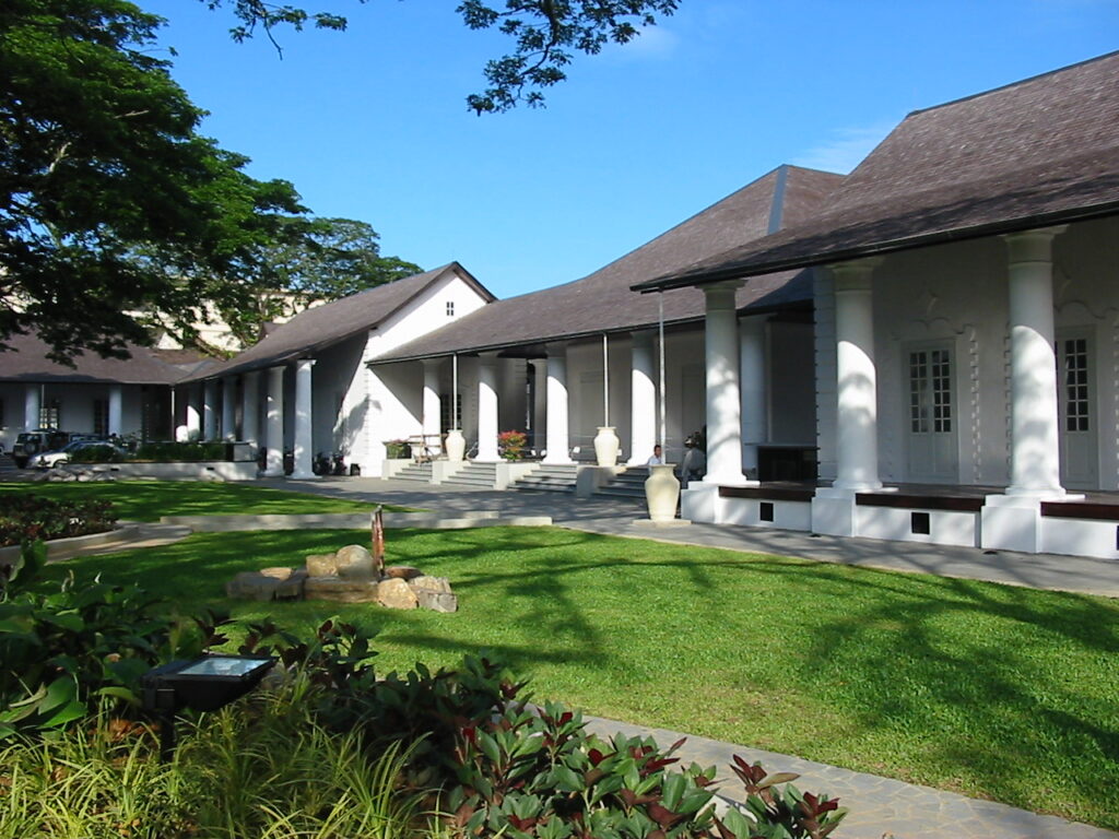 White colonnaded colonial buildings around a lawn at the Kuching Old Courthouse