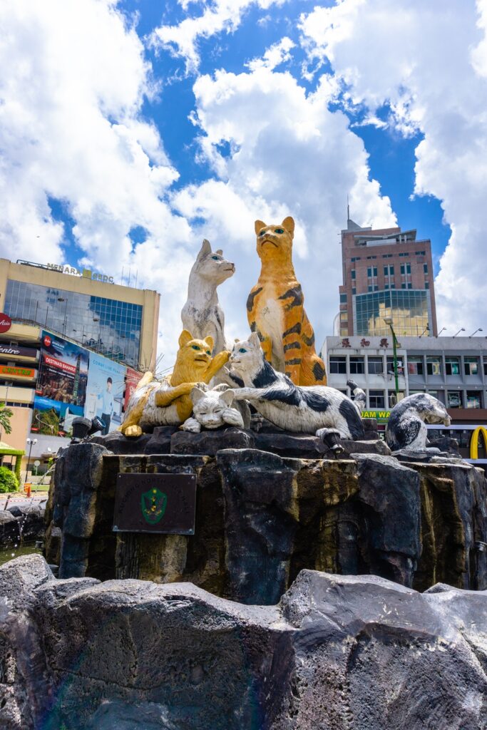 Group of painted cat sculptures on a rock fountain at a Kuching road junction
