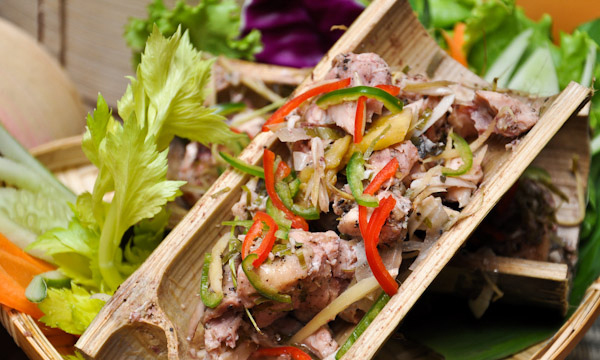 Chicken cooked in split bamboo tubes topped with red and green chilli and ginger