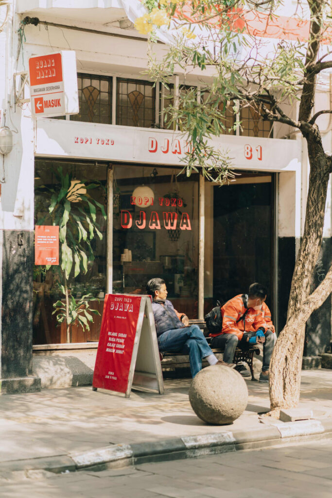 Customers seated outside Kopi Toko Djawa, a red-signed corner coffee shop on Jalan Braga