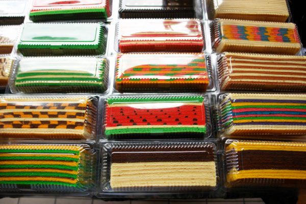 Packaged slices of Sarawak layer cake in colourful geometric patterns stacked on a counter