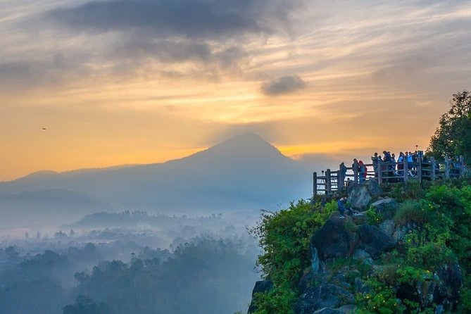 Visitors on a clifftop viewing platform above a mist-filled valley at sunrise