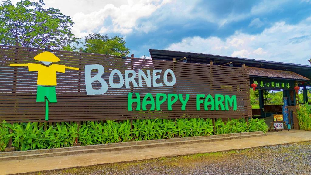 Timber fence signed Borneo Happy Farm with a yellow scarecrow figure and planting in front
