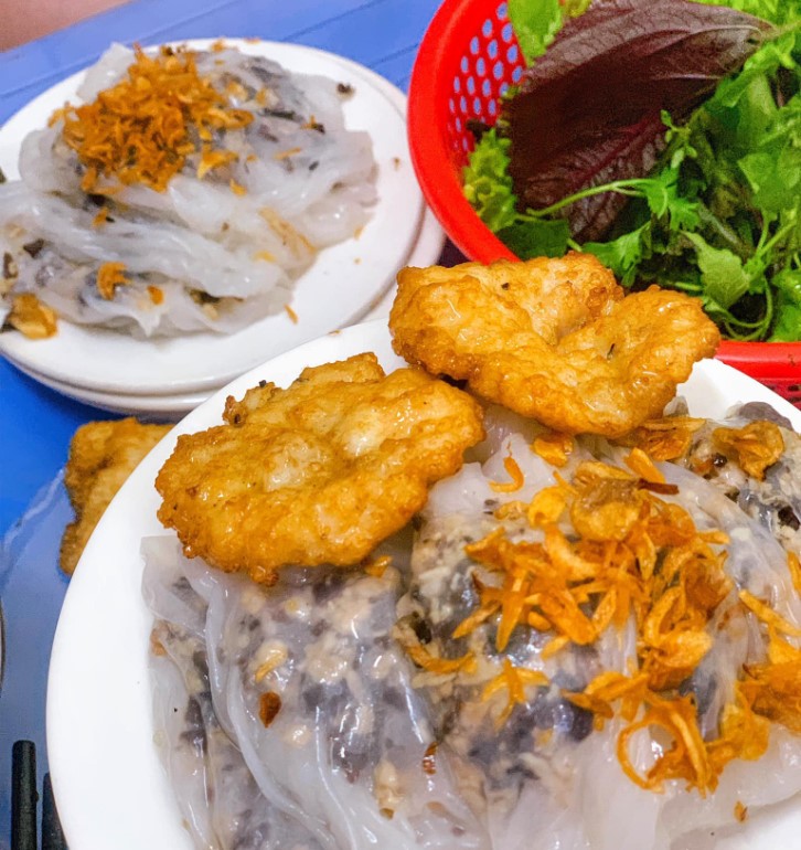 Steamed rice rolls topped with fried shallots, served with fried squid cake and fresh herbs
