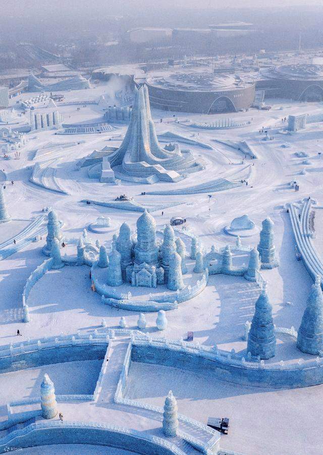 Aerial daytime view of ice and snow sculptures spread across a snow-covered park in Harbin