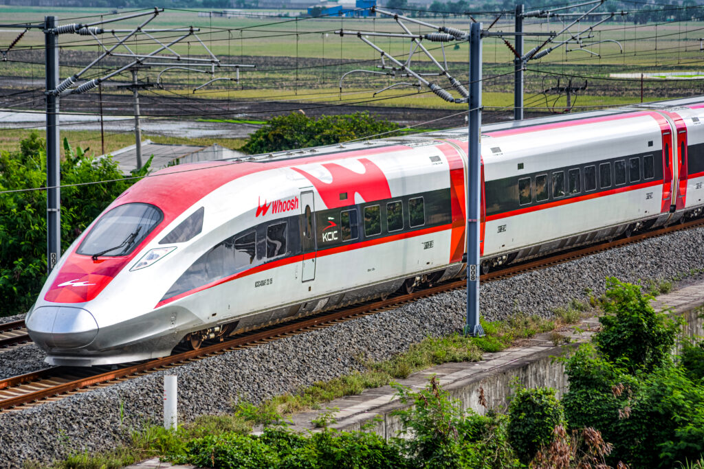 Red and white Whoosh high-speed train running past paddy fields on the Jakarta to Bandung line