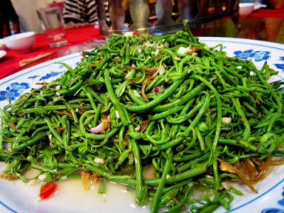 Plate piled with stir-fried midin jungle fern and fried shallots