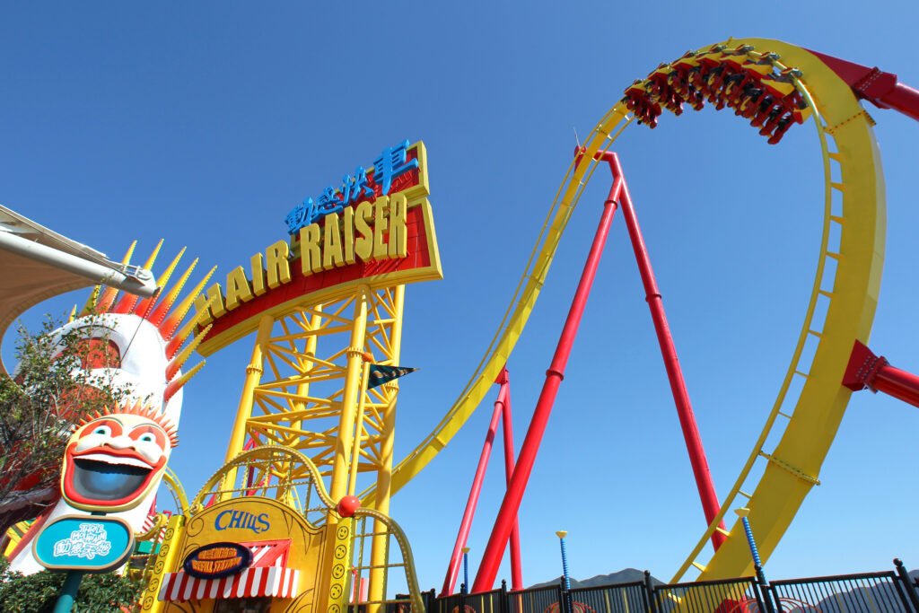Riders upside down on the yellow loop of the Hair Raiser floorless coaster against a blue sky