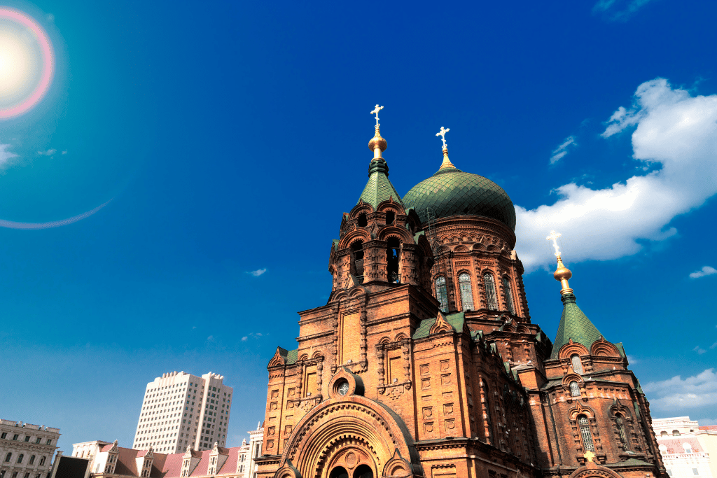 The brick facade and green onion domes of Saint Sophia Cathedral against a blue sky