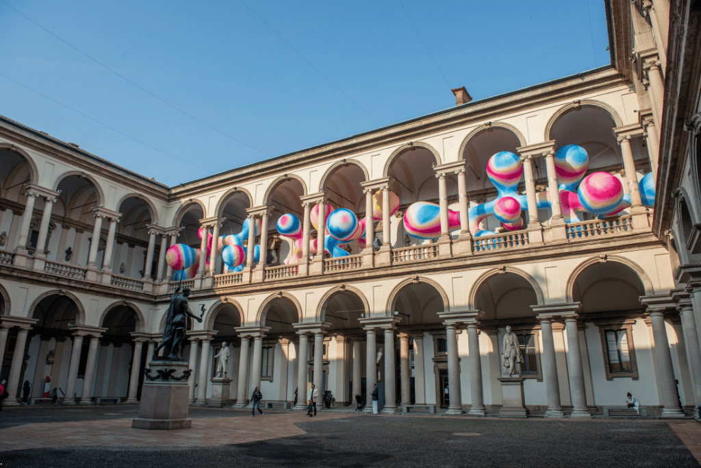 Arcaded courtyard of Palazzo Brera with a colourful sculpture installation, Milan
