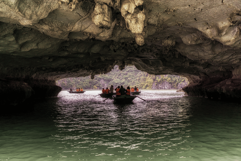 Tourists in orange life jackets rowed through a low limestone tunnel into a lagoon