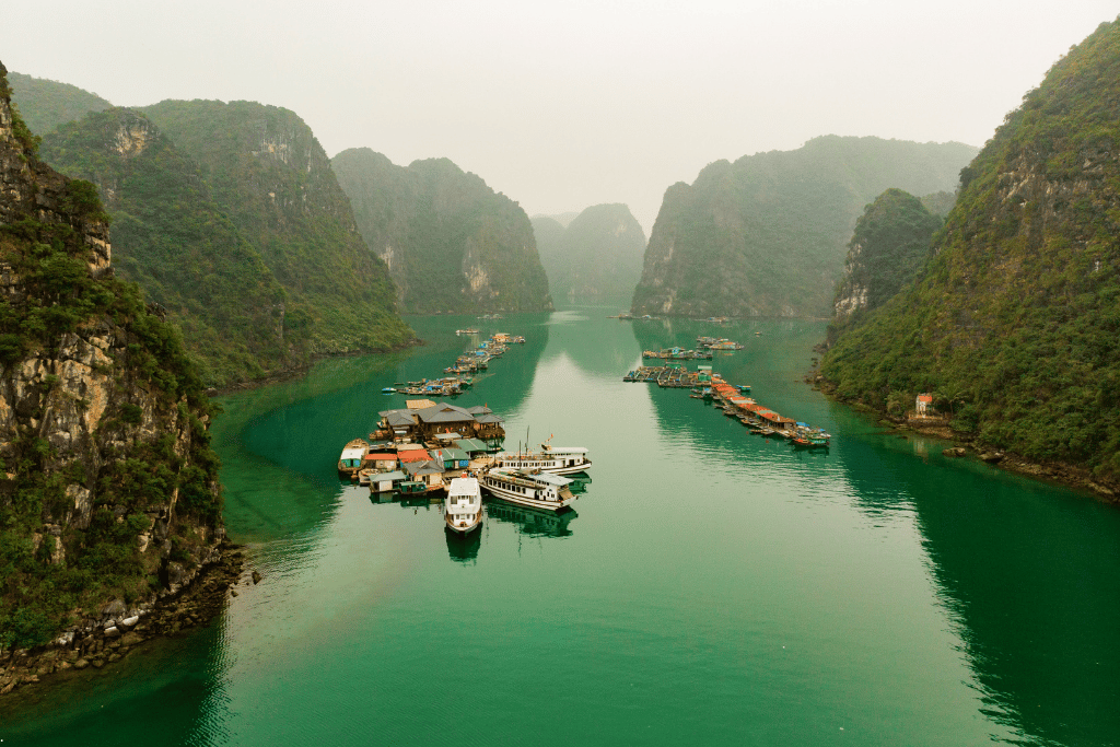 Aerial view of floating houses and boats moored in a misty channel between karst islands