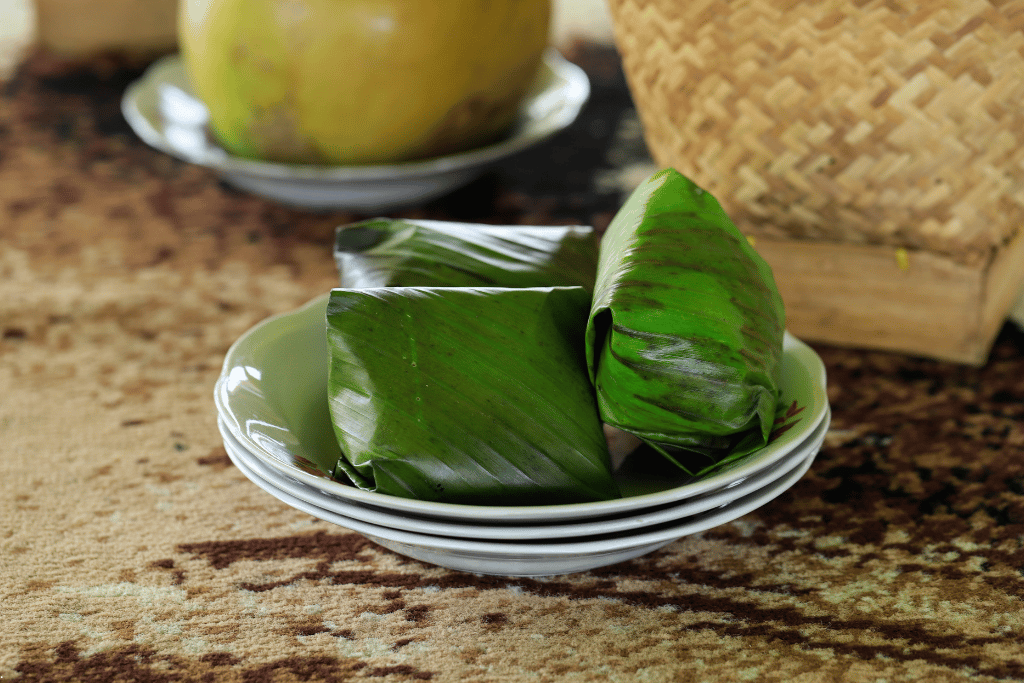 Banana-leaf parcels of nasi timbel stacked on white plates