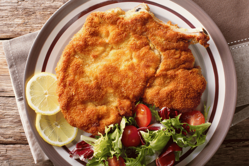 A golden breaded cotoletta alla Milanese served with lemon and salad