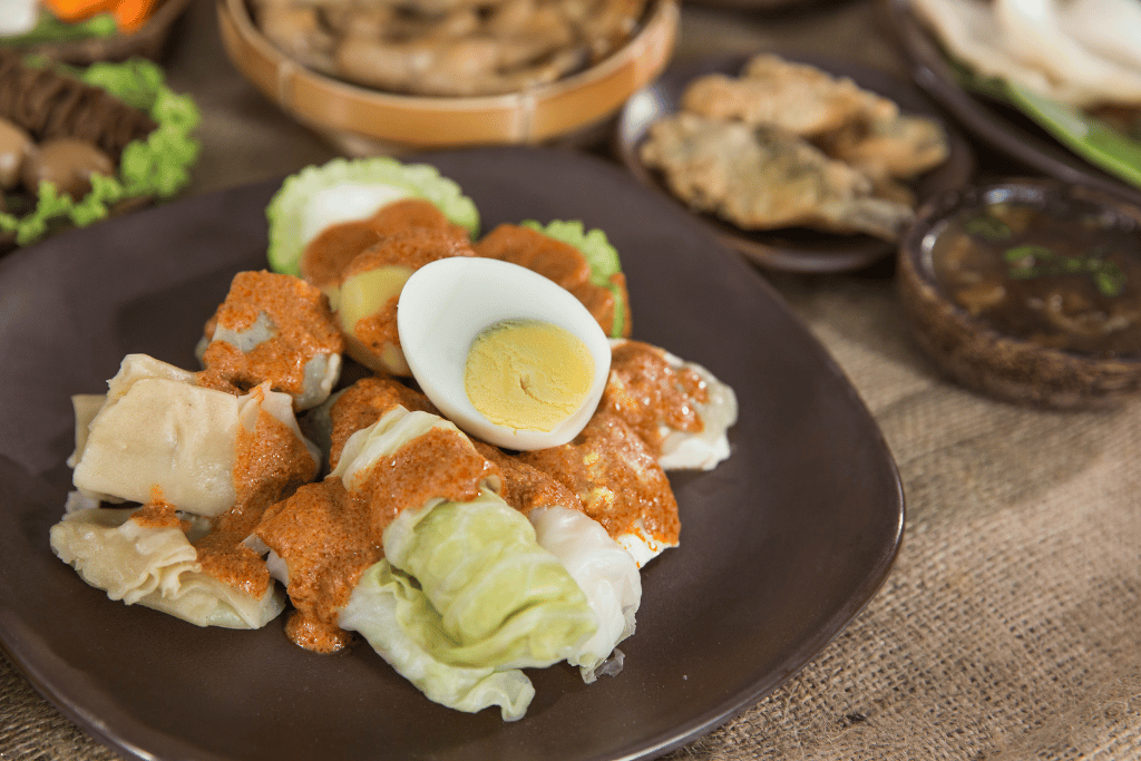 Steamed siomay with cabbage, potato and a halved boiled egg under peanut sauce