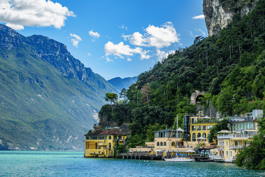 Yellow lakeside buildings and moored boats beneath steep mountains on Lake Garda