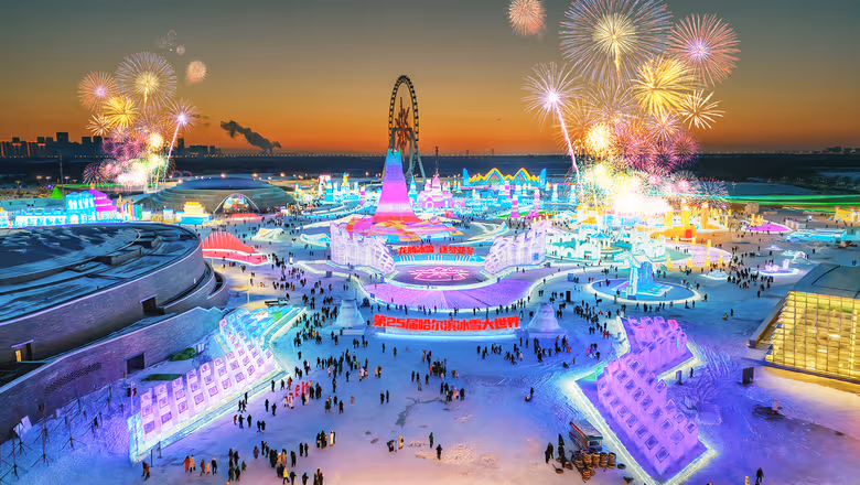 Dusk panorama of Harbin Ice and Snow World with a Ferris wheel, fireworks and crowds