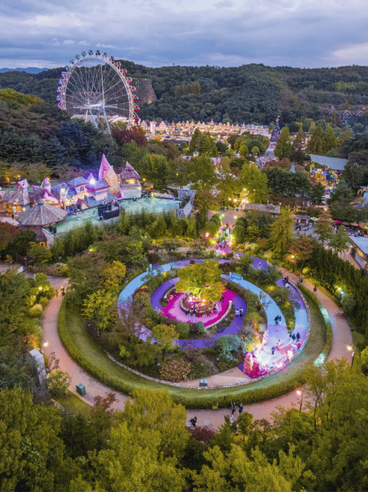 Aerial view of Everland at dusk, Ferris wheel above illuminated circular flower gardens