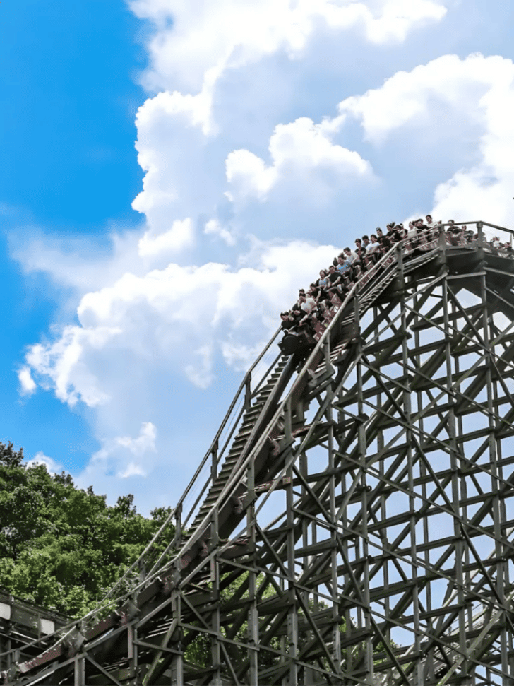 Riders crest the lift hill of Everland's wooden roller coaster against a blue sky