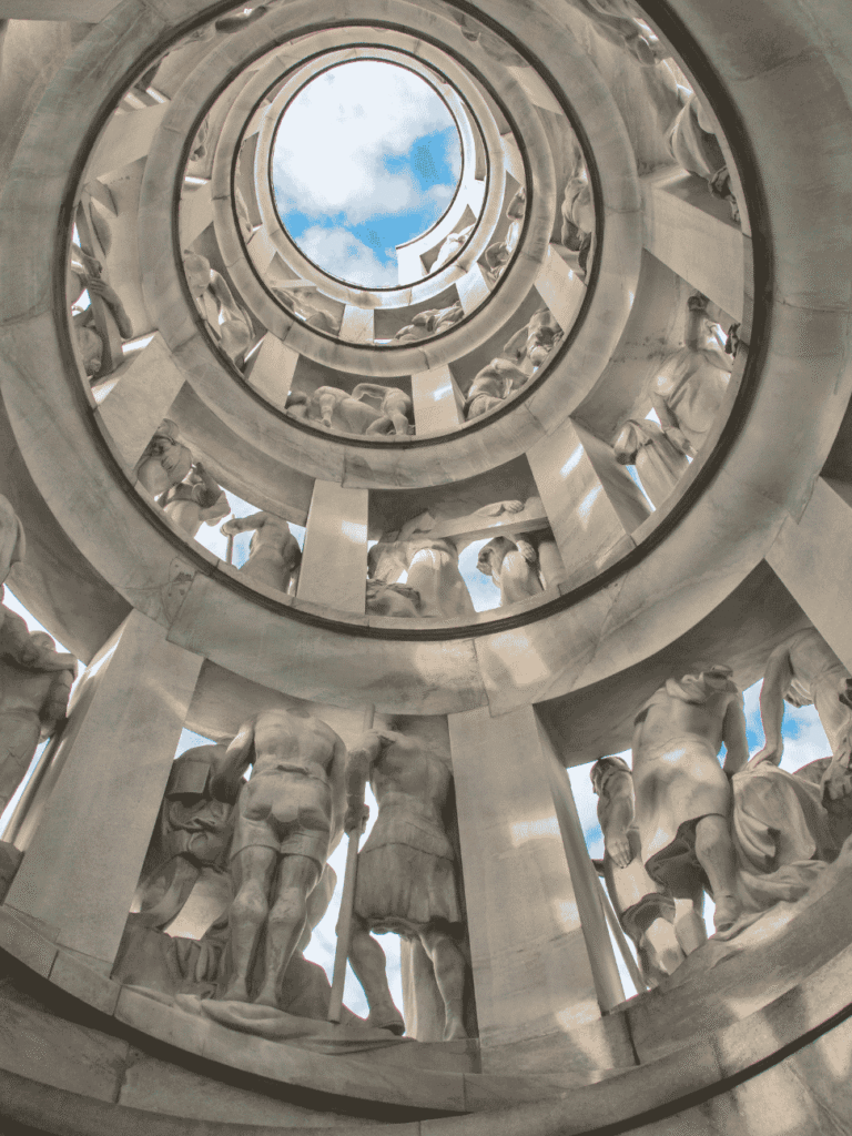 Tiers of classical stone statues spiralling up to a circular skylight inside a domed monument