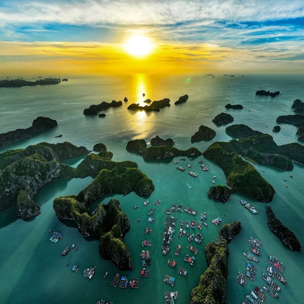 Aerial sunset view of floating fish farms scattered on the water between karst islands