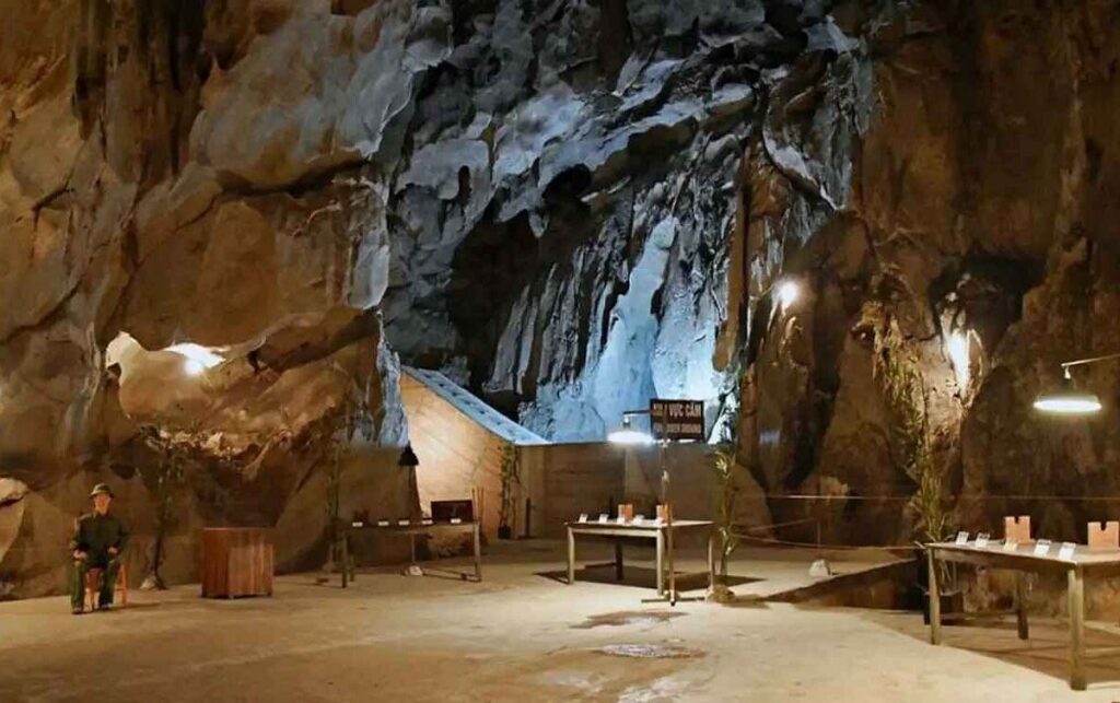 Cave interior fitted out with concrete rooms, display tables and a seated uniformed figure