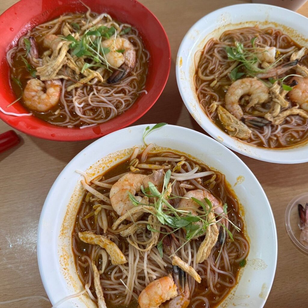 Three bowls of Sarawak laksa with prawns, shredded chicken, bean sprouts and coriander