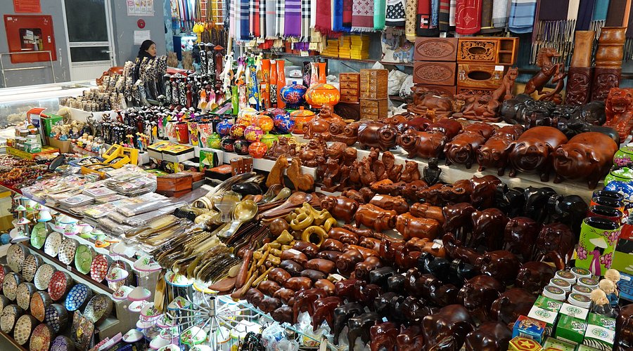 Market stall stacked with carved wooden animals, lacquerware and souvenirs