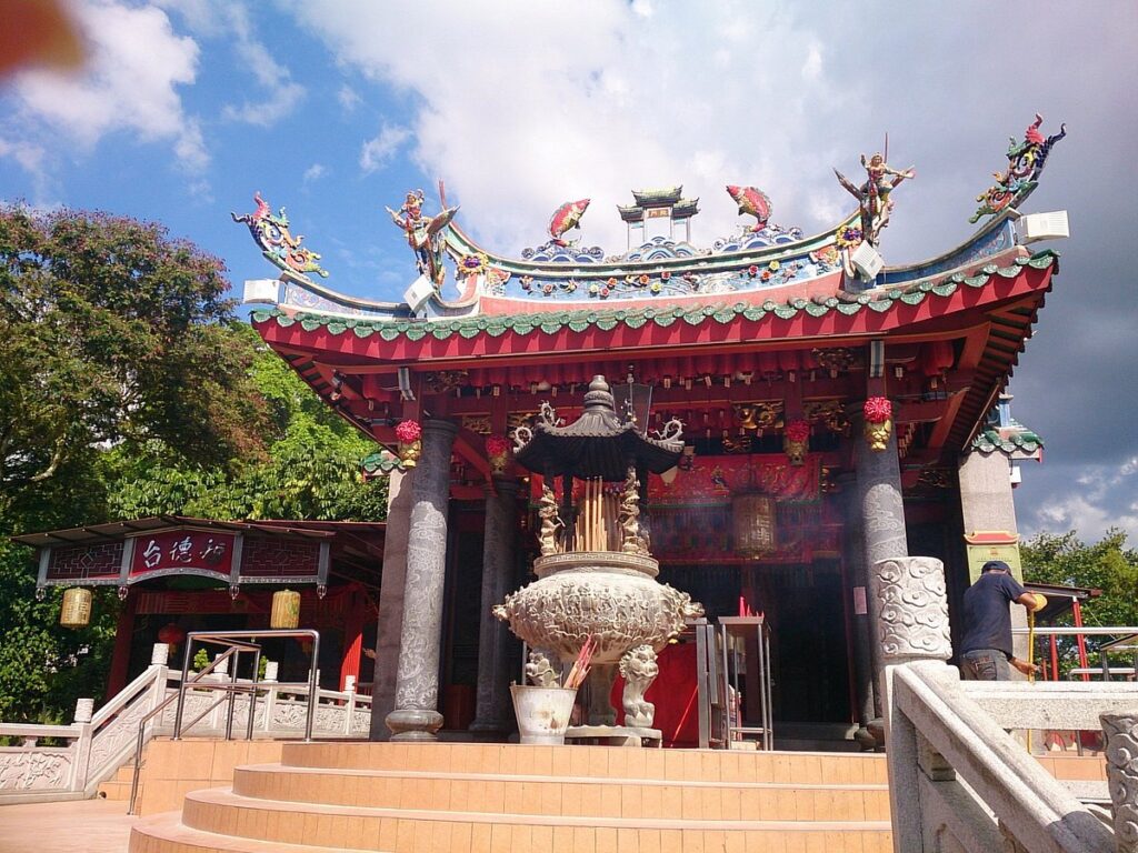 Tua Pek Kong Temple with dragon roof figures and a large stone incense urn full of joss sticks