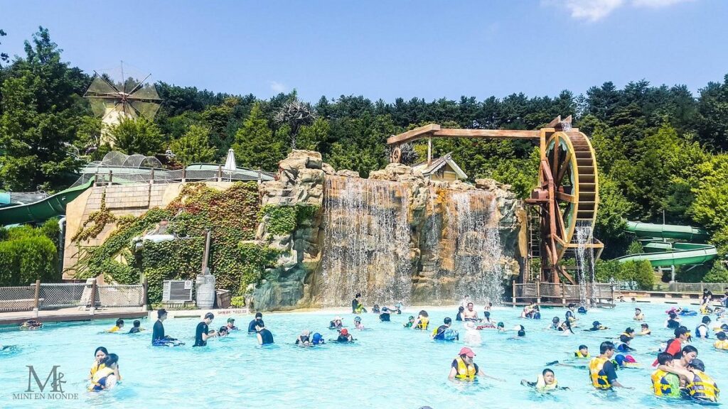 Crowded wave pool at Caribbean Bay below a rock waterfall and wooden waterwheel